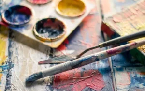 Paintbrushes, paint palette, and canvas representing the AP Art and Design Exam and portfolio preparation.